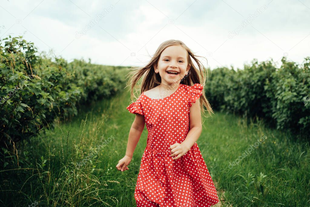 Beautiful Little Girl Dressed in Red Polka Dot Dress, Having Fun Time in Field Outside the City, Childhood Concept