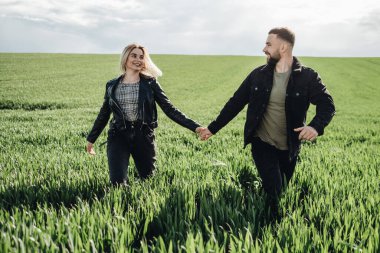 Siyah Deri ve Kot Ceketli Mutlu Genç Çift Yeşil Tarlada Eğleniyor