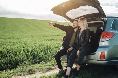 Siyah Deri ve Kot Ceketli Mutlu Genç Gezgin Çift Yeşil Tarlada Yolculuk Yapıyor