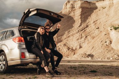 Siyah Deri ve Kot Ceket Giymiş Mutlu Genç Gezgin Çifti Şehir dışında Gezintide Eğleniyor