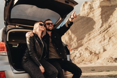 Siyah Deri ve Kot Ceket Giymiş Mutlu Genç Gezgin Çifti Şehir dışında Gezintide Eğleniyor