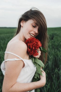 Beyaz elbiseli güzel kızın portresini kapat Kırmızı Şakayık Buketi