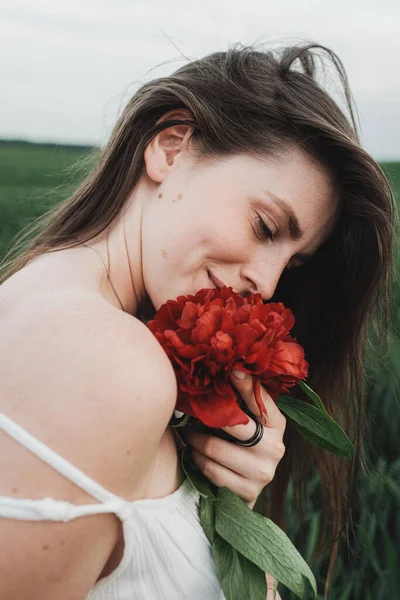 白いドレスの若い美しい少女の肖像画を閉じる赤い牡丹の花束を保持 — ストック写真