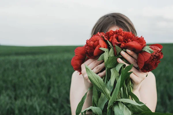 白いドレスの若い美しい少女の肖像画を閉じる赤い牡丹の花束を保持 — ストック写真