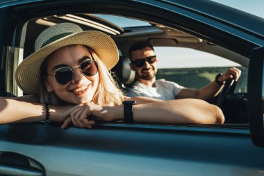 Happy Young Couple Sitting Inside Their Car Enjoying Road Trip, Travel and Adventure Concept clipart