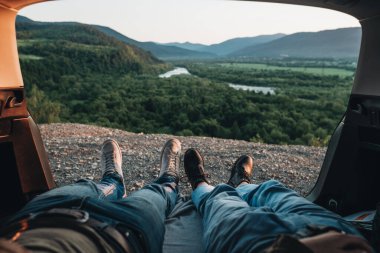Arabalarının bagajında yatan ve Horizon 'daki yolculuğun, dağların ve nehrin tadını çıkaran mutlu çiftin arka görüntüsü.