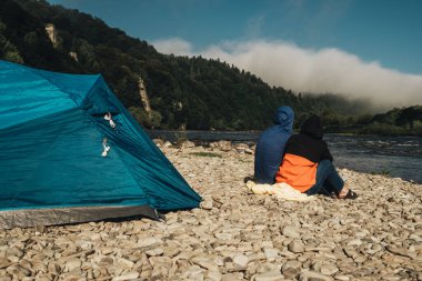 Nehir kenarında kamp yapan genç çift.