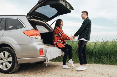 Genç ve güzel bir çift, Araba, Seyahat ve Yolculuk Konsepti 'nin yanında eğleniyor.