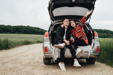 Genç ve güzel bir çift Araba bagajında oturuyor ve yolculuğun tadını çıkarıyor.