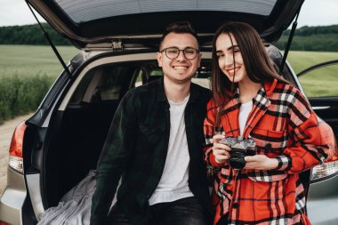 Genç ve güzel bir çift Araba bagajında oturuyor ve yolculuğun tadını çıkarıyor.