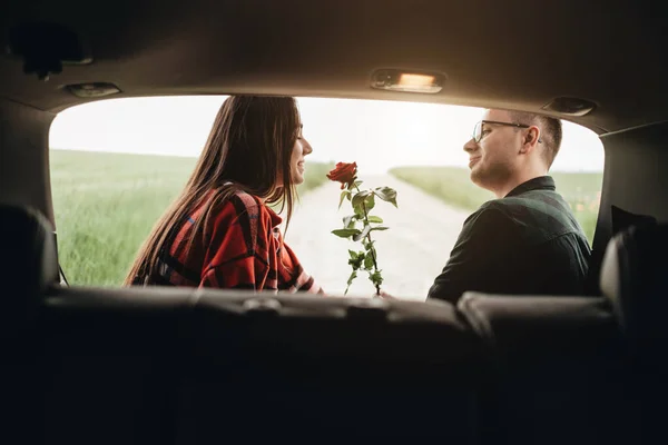纵观整个车场 年轻貌美的情侣享受路途 女孩抱着玫瑰 浪漫的心情 — 图库照片