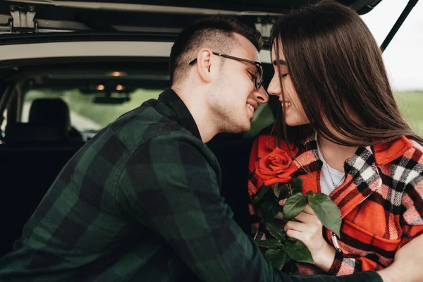 年轻美丽的情侣们坐在车架上 享受路途 抱着玫瑰的女孩 浪漫的心情 — 图库照片