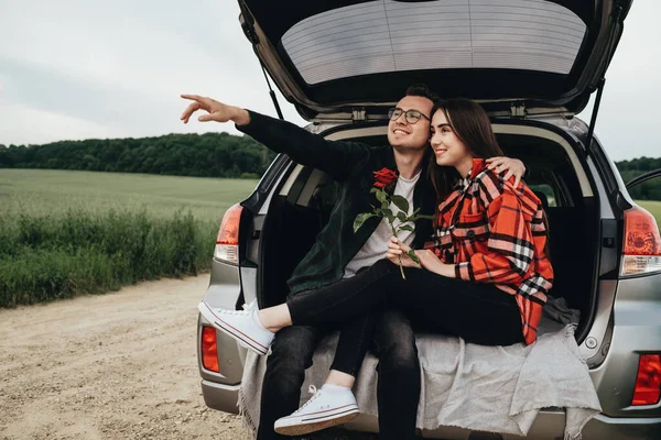 年轻美丽的情侣们坐在车架上 享受路途 抱着玫瑰的女孩 浪漫的心情 — 图库照片