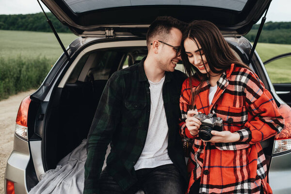 Молодая красивая пара сидит в багажнике и наслаждается поездкой
