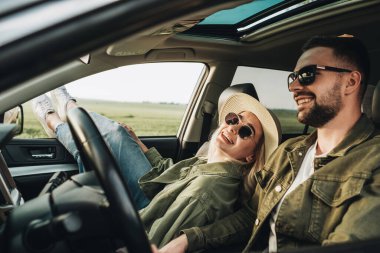 Kadın ve erkek arabada oturuyor, eğleniyor ve macera yolculuğunun tadını çıkarıyorlar.