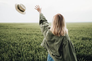 Beyaz tişörtlü güzel bir kızın portresi ve Yeşil Tarlada Hasır Şapkalı zeytin rengi ceket.