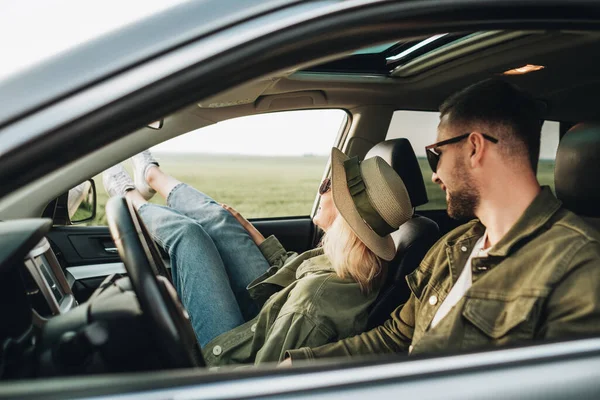 Kadın ve erkek arabada oturuyor, eğleniyor ve macera yolculuğunun tadını çıkarıyorlar.