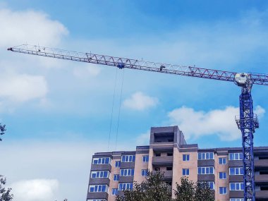 Konut Kompleksi inşaatı. Çok katlı binanın inşaatı. Mavi gökyüzüne karşı vinç ve bina inşaatı.