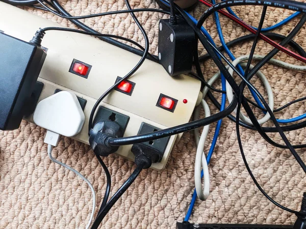 Electrical cord. Overloaded power boards. Many electrical cords connected to a power boards. Cable power cords in a tangled mess on floor workplace.