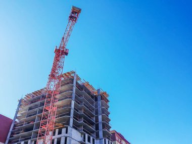 Konut Kompleksi inşaatı. Çok katlı binanın inşaatı. Mavi gökyüzüne karşı vinç ve bina inşaatı.