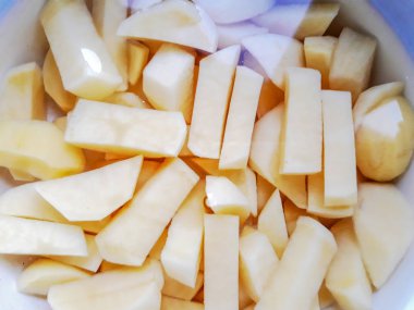 Kaynaması için suda patates kesin. Su ile tavada patates dilimleri.