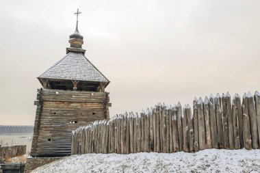 Eski çitleri olan ahşap eski bir kilise ya da gökyüzünün arka planına dayanan çitler. Sert grunge sivri uçlu kütükler. Manzara. Kış. Kar yağışıName.