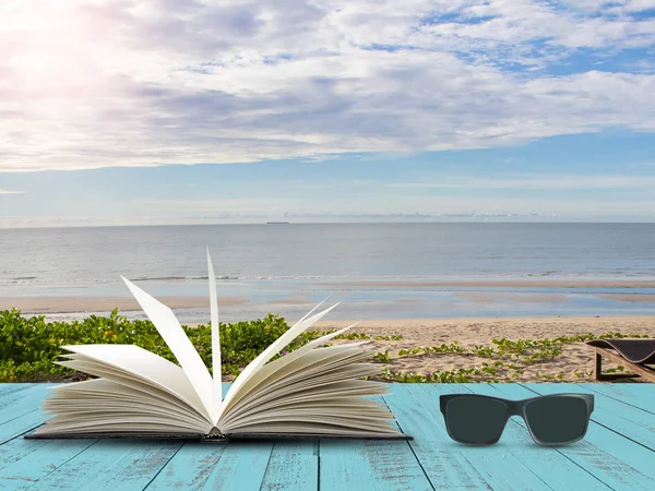 Mavi ahşap tahta deniz plaj arka plan üzerinde siyah güneş cam açık kitap