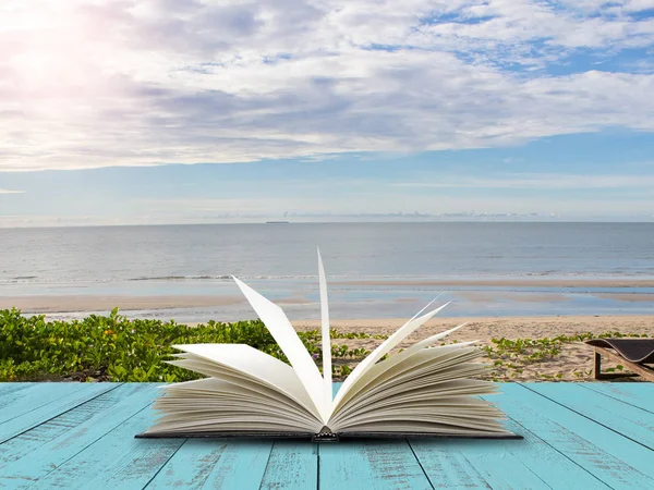 Deniz plaj arka plan ile mavi ahşap tahta üzerinde açık kitap