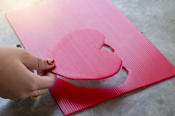 Donne mano rosa cuore sulla tavola rossa — Foto Stock