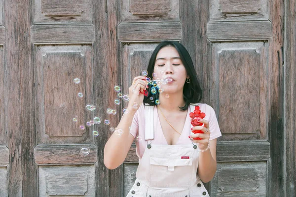 Porträtt av ung glad asiatisk kvinna att göra såpbubblor — Stockfoto