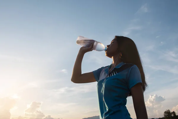 Young Asian Woman Drinking Water After Jogging