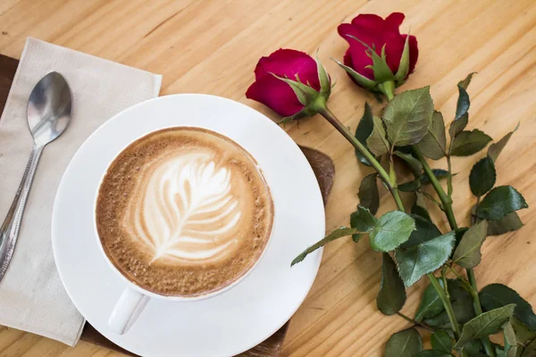 Secangkir kopi, mawar merah di atas meja kayu — Stok Foto