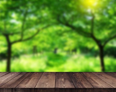 Bulanıklık yeşil yaprakları bokeh arka plan ile boş ahşap güverte masa
