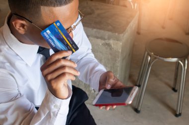Asyalı iş adamı akıllı telefonuyla online alışveriş yapmak için beşik kartını kullanıyor