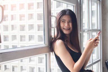 Kafede telefonla gülümseyen Asyalı kadınlar.