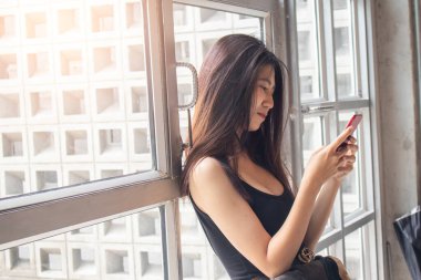 Kafede telefon kullanan mutlu Asyalı kadınlar.