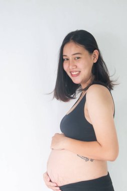 Çekici hamile kadın ayakta ve karnını tutuyor.