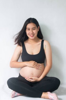 Çekici hamile kadın oturuyor ve karnını tutuyor.