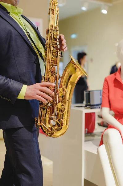 musician plays the saxophone performance at a concert in shopping center of women\'s clothing store on holiday