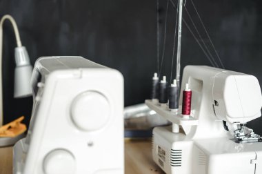 Terzinin masasında iki beyaz dikiş makinesi var.