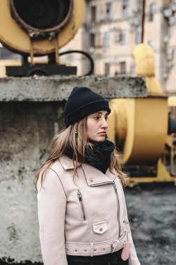 Siyah kot pantolon, şapka ve pembe bir ceket, bir harap kentsel çatı konum kadın. Güzellik moda ve stil. cep telefonu şık bir durumda