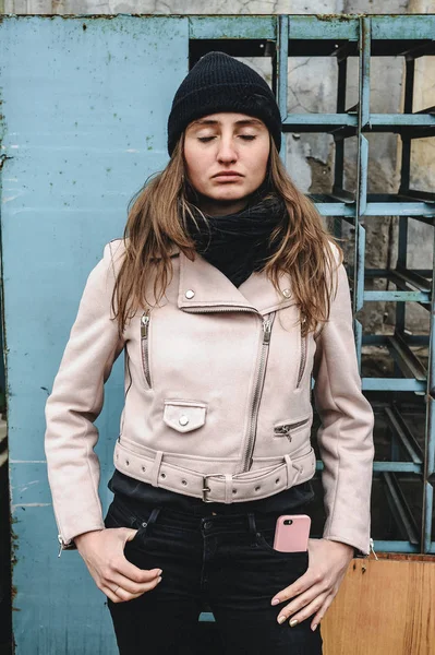 Siyah kot pantolon, şapka ve pembe bir ceket, bir harap kentsel çatı konum kadın. Güzellik moda ve stil. cep telefonu şık bir durumda