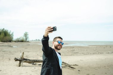 Gençlik giysilerle giyinmiş genç sakallı adam, deniz kenarındaki sıcak yaz gününde macera seyahat.