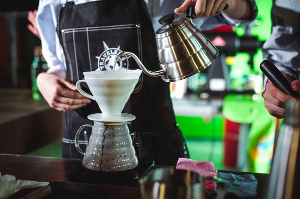 championship among coffee houses, members of teams show barista\'s skill, prepare drinks, teamwork. pours water from a kettle