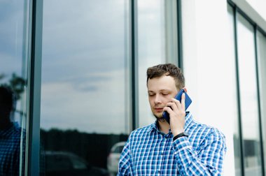 damlanmış saçlı, sakallı, mavi damalı gömlek giymiş genç bir adamın portresi