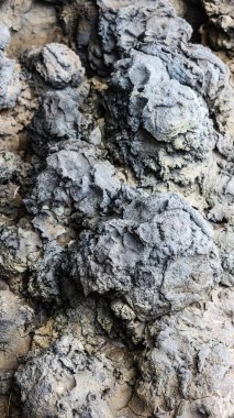 engebeli, topak topak volkanik kaya yüzeyinin dikey görüntüsü toprak ve kahverengi tonlarda karmaşık doğal dokular ve erozyon desenleri sergiliyor, jeolojik harikalar ve ham toprak elementlerini çağrıştırıyor.