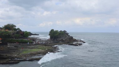 Tanah Lot, Beraban, Kediri, Tabanan Regency, Bali, Endonezya - 18 Ağustos 2025: Antik Hindu hac tapınağı Pura Tanah Lot 'un sahil kıyısında birçok turistle birlikte inşa edilmiş geniş bir görüntüsü