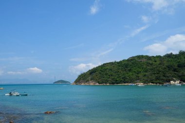 Peng Chau, Lantau Island, Hong Kong- 20 Apr 2025: outdoor beach by the seaside with blue sky and sea and ships sailing