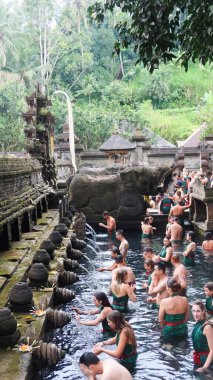 Pura Tirta Empul,Tampaksiring,  Bali, Indonesia- 19 Aug 2025: famous Hindu water temple for worshiping and many tourists praying cleansing in the holy spring in the pool and water coming from fountain