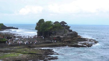 Tanah Lot, Beraban, Kediri, Tabanan Regency, Bali, Endonezya - 18 Ağustos 2025: Antik Hindu hac tapınağı Pura Tanah Lot 'un sahil kıyısında birçok turistle birlikte inşa edilmiş geniş bir görüntüsü